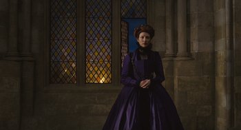 Movie still from “Elizabeth: The Golden Age” (2007), directed by Shekhar Kapur – A woman in a purple dress standing in front of stained glass windows; Medium shot, Low angle