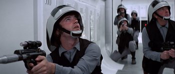 Movie still from “Star Wars: Episode IV - A New Hope” (1977), directed by George Lucas – A man wearing a helmet while holding a gun in his hand; Close Up shot, Low angle