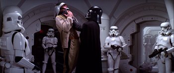 Movie still from “Star Wars: Episode IV - A New Hope” (1977), directed by George Lucas – A group of people standing next to each other in a room; Medium shot, Over the shoulder angle