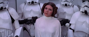 Movie still from “Star Wars: Episode IV - A New Hope” (1977), directed by George Lucas – A woman in a star wars costume standing in front of some white statues; Medium shot, Over the shoulder angle