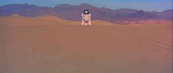 Movie still from “Star Wars: Episode IV - A New Hope” (1977), directed by George Lucas – An r 2 d 2 robot is standing in the desert; Extreme Wide shot, Low angle