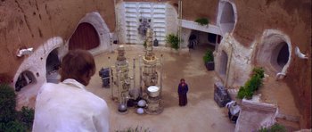 Movie still from “Star Wars: Episode IV - A New Hope” (1977), directed by George Lucas – A man standing in a courtyard with a bunch of pipes; Wide shot, High angle