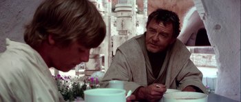 Movie still from “Star Wars: Episode IV - A New Hope” (1977), directed by George Lucas – Two people sitting at a table with a plate of food; Medium shot, Over the shoulder angle