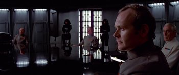 Movie still from “Star Wars: Episode IV - A New Hope” (1977), directed by George Lucas – A group of people standing around a table; Medium shot, Over the shoulder angle