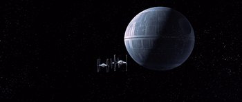Movie still from “Star Wars: Episode IV - A New Hope” (1977), directed by George Lucas – Two star wars ships in front of a death star; Extreme Wide shot, Low angle