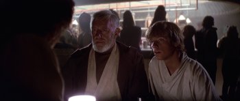 Movie still from “Star Wars: Episode IV - A New Hope” (1977), directed by George Lucas – Two people in a room with a crowd of onlookers in the background; Medium shot, Over the shoulder angle