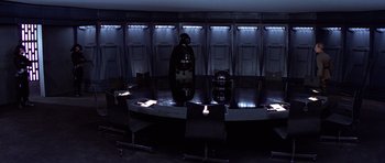 Movie still from “Star Wars: Episode IV - A New Hope” (1977), directed by George Lucas – A man standing in front of a round conference table; Wide shot, High angle