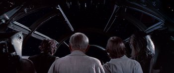 Movie still from “Star Wars: Episode IV - A New Hope” (1977), directed by George Lucas – A group of people standing in front of a star field at night; Medium shot, Low angle