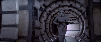 Movie still from “Star Wars: Episode IV - A New Hope” (1977), directed by George Lucas – A man in a star wars costume walking through a tunnel; Wide shot, Low angle