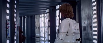Movie still from “Star Wars: Episode IV - A New Hope” (1977), directed by George Lucas – A man in a white suit standing next to a wall; Medium shot, Over the shoulder angle