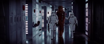 Movie still from “Star Wars: Episode IV - A New Hope” (1977), directed by George Lucas – A group of star wars characters walking down a hallway; Wide shot, Low angle