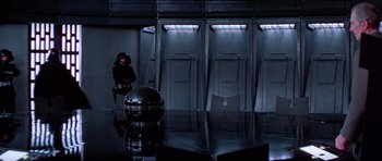 Movie still from “Star Wars: Episode IV - A New Hope” (1977), directed by George Lucas – A man standing in front of a row of urinals in a room; Wide shot, Low angle