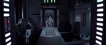 Movie still from “Star Wars: Episode IV - A New Hope” (1977), directed by George Lucas – A group of people standing inside of a building; Wide shot, Low angle