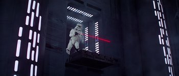 Movie still from “Star Wars: Episode IV - A New Hope” (1977), directed by George Lucas – A star wars character is standing on a platform; Wide shot, Low angle