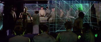 Movie still from “Star Wars: Episode IV - A New Hope” (1977), directed by George Lucas – A group of people standing in front of a screen; Wide shot, High angle