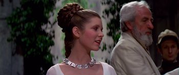Movie still from “Star Wars: Episode IV - A New Hope” (1977), directed by George Lucas – A woman with a silver necklace and a braid in her hair looking to her left; Close Up shot, Over the shoulder angle