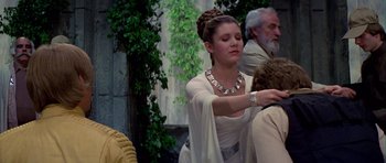 Movie still from “Star Wars: Episode IV - A New Hope” (1977), directed by George Lucas – A woman in a white dress is putting a necklace on; Medium shot, Over the shoulder angle