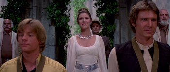 Movie still from “Star Wars: Episode IV - A New Hope” (1977), directed by George Lucas – A woman in a white dress standing next to a man in a black suit; Medium shot, Low angle