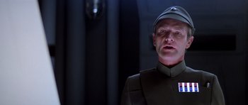 Movie still from “Star Wars: Episode V - The Empire Strikes Back” (1980), directed by Irvin Kershner – A man wearing a uniform and a hat is standing up; Close Up shot, Low angle
