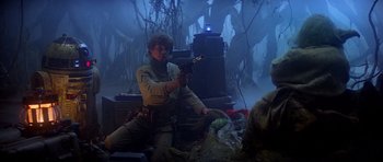 Movie still from “Star Wars: Episode V - The Empire Strikes Back” (1980), directed by Irvin Kershner – A man holding a gun while sitting on the ground; Medium shot, Low angle