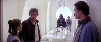 Movie still from “Star Wars: Episode V - The Empire Strikes Back” (1980), directed by Irvin Kershner – A man standing in front of a table with a darth vader and a stormtrooper; Medium shot, Over the shoulder angle