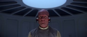 Movie still from “Star Wars: Episode V - The Empire Strikes Back” (1980), directed by Irvin Kershner – A bald man wearing headphones in front of a wall; Close Up shot, Low angle