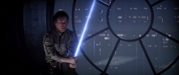 Movie still from “Star Wars: Episode V - The Empire Strikes Back” (1980), directed by Irvin Kershner – A man holding a lightsaber while standing in front of a building; Medium shot, Low angle