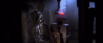 Movie still from “Star Wars: Episode VI - Return of the Jedi” (1983), directed by Richard Marquand – A robot standing in front of an iron object; Wide shot, Low angle
