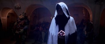 Movie still from “Star Wars: Episode VI - Return of the Jedi” (1983), directed by Richard Marquand – A man in a hooded cloak standing in a dark room; Medium shot, Low angle