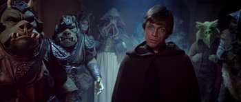 Movie still from “Star Wars: Episode VI - Return of the Jedi” (1983), directed by Richard Marquand – A man standing in front of a group of people; Medium shot, Over the shoulder angle