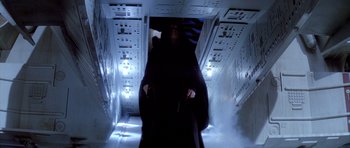 Movie still from “Star Wars: Episode VI - Return of the Jedi” (1983), directed by Richard Marquand – A man in a black robe walking down a hallway; Wide shot, Low angle