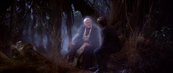 Movie still from “Star Wars: Episode VI - Return of the Jedi” (1983), directed by Richard Marquand – A man sitting next to another man in the woods; Medium shot, Over the shoulder angle