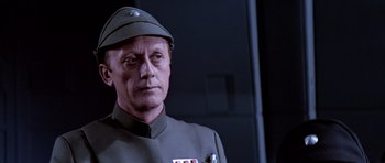 Movie still from “Star Wars: Episode VI - Return of the Jedi” (1983), directed by Richard Marquand – A man in a uniform and a hat is looking at the camera; Close Up shot, Low angle