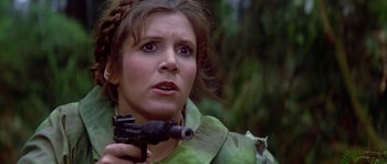 Movie still from “Star Wars: Episode VI - Return of the Jedi” (1983), directed by Richard Marquand – A person holding a gun in a forest; Close Up shot, Low angle