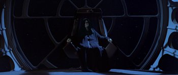 Movie still from “Star Wars: Episode VI - Return of the Jedi” (1983), directed by Richard Marquand – An emperor palpatine sitting in a chair in the dark; Wide shot, High angle