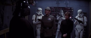 Movie still from “Star Wars: Episode VI - Return of the Jedi” (1983), directed by Richard Marquand – A man in a uniform standing in front of a group of stormtroopers; Medium shot, Over the shoulder angle