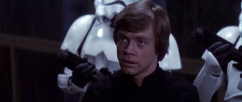 Movie still from “Star Wars: Episode VI - Return of the Jedi” (1983), directed by Richard Marquand – A man in black shirt holding a gun in a room; Close Up shot, Over the shoulder angle