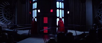 Movie still from “Star Wars: Episode VI - Return of the Jedi” (1983), directed by Richard Marquand – Two people dressed in red are standing in front of a building; Extreme Wide shot, Low angle