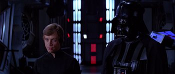 Movie still from “Star Wars: Episode VI - Return of the Jedi” (1983), directed by Richard Marquand – Darth vader standing next to luke skywalker in a dark room; Close Up shot, Over the shoulder angle