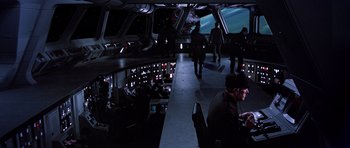 Movie still from “Star Wars: Episode VI - Return of the Jedi” (1983), directed by Richard Marquand – A group of people sitting in a room with a space ship in the background; Wide shot, High angle