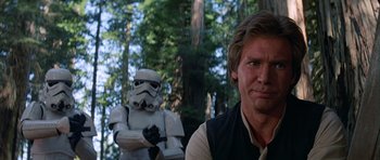Movie still from “Star Wars: Episode VI - Return of the Jedi” (1983), directed by Richard Marquand – A man standing next to a stormtrooper statue; Close Up shot, Over the shoulder angle