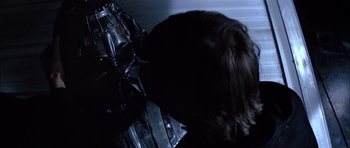 Movie still from “Star Wars: Episode VI - Return of the Jedi” (1983), directed by Richard Marquand – A person with long brown hair is looking at a metal object; Close Up shot, Over the shoulder angle