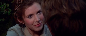 Movie still from “Star Wars: Episode VI - Return of the Jedi” (1983), directed by Richard Marquand – A woman looking into the camera with a man in front of her; Close Up shot, Over the shoulder angle