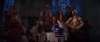 Movie still from “Star Wars: Episode VI - Return of the Jedi” (1983), directed by Richard Marquand – A group of people standing around a star wars character; Wide shot, Low angle