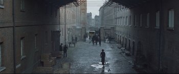 Movie still from “Suffragette” (2015), directed by Sarah Gavron – A man standing in the middle of an alley way; Extreme Wide shot, High angle