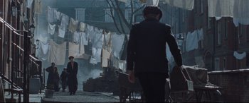 Movie still from “Suffragette” (2015), directed by Sarah Gavron – A man walking down the street with a cart full of clothes; Wide shot, High angle