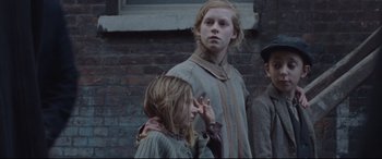 Movie still from “Suffragette” (2015), directed by Sarah Gavron – A group of people standing next to each other on a street; Medium shot, Low angle
