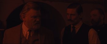 Movie still from “Suffragette” (2015), directed by Sarah Gavron – Two men in suits and ties standing next to each other; Medium shot, Over the shoulder angle