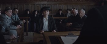 Movie still from “Suffragette” (2015), directed by Sarah Gavron – A person in a courtroom wearing a black hat; Medium shot, Low angle