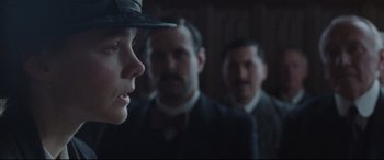 Movie still from “Suffragette” (2015), directed by Sarah Gavron – A group of men standing next to each other in a room; Close Up shot, Over the shoulder angle